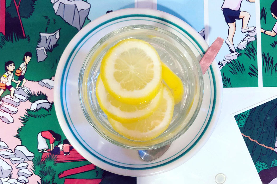 Photo of lemons in a cup on a glass table with multiple printed pages from the comic laid underneath the glass
