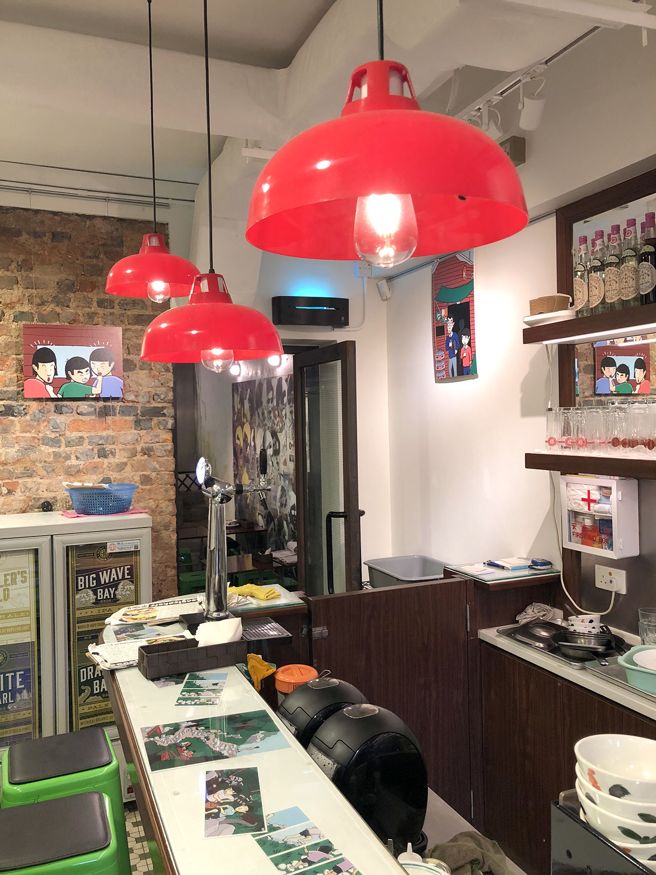 Inside view of the cafe with signature red half-circle hanging lanterns with printed panels from the comic on the walls and on the glass tables