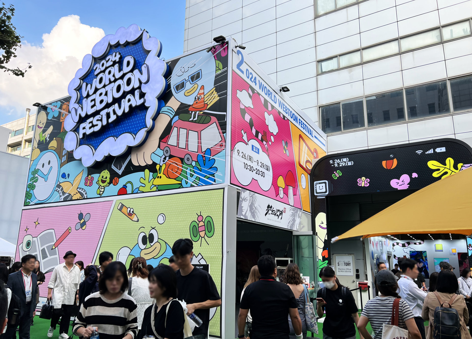 Visitors stream in and out of the colorful entrance to the 2024 World Webtoon Festival.